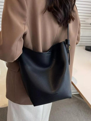 Black minimalist PU leather shoulder bag with adjustable strap and gold buckle detail.