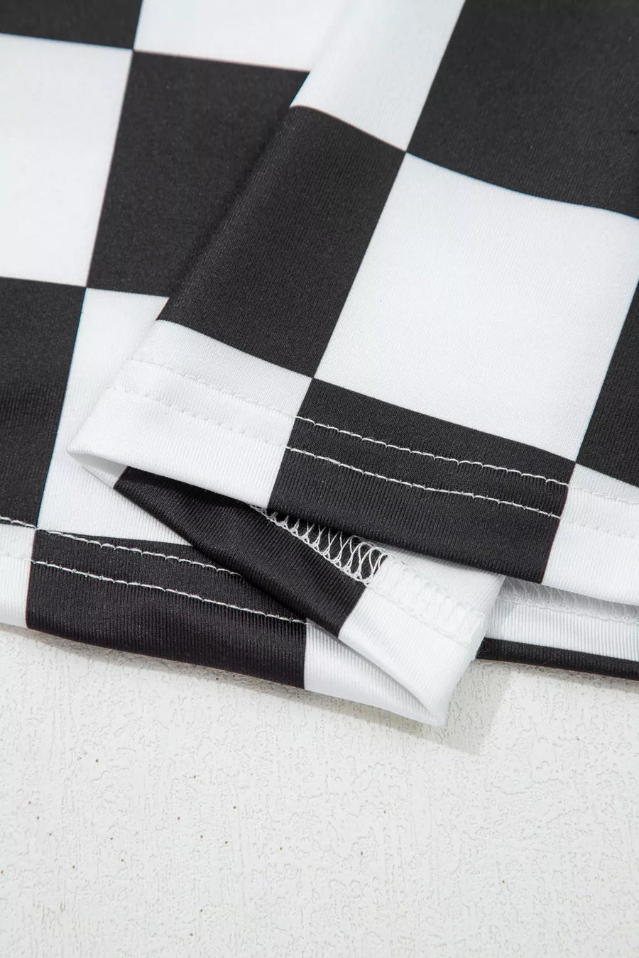 Graphic checkerboard seamless tank top in black and white polyester with visible stitching detail.