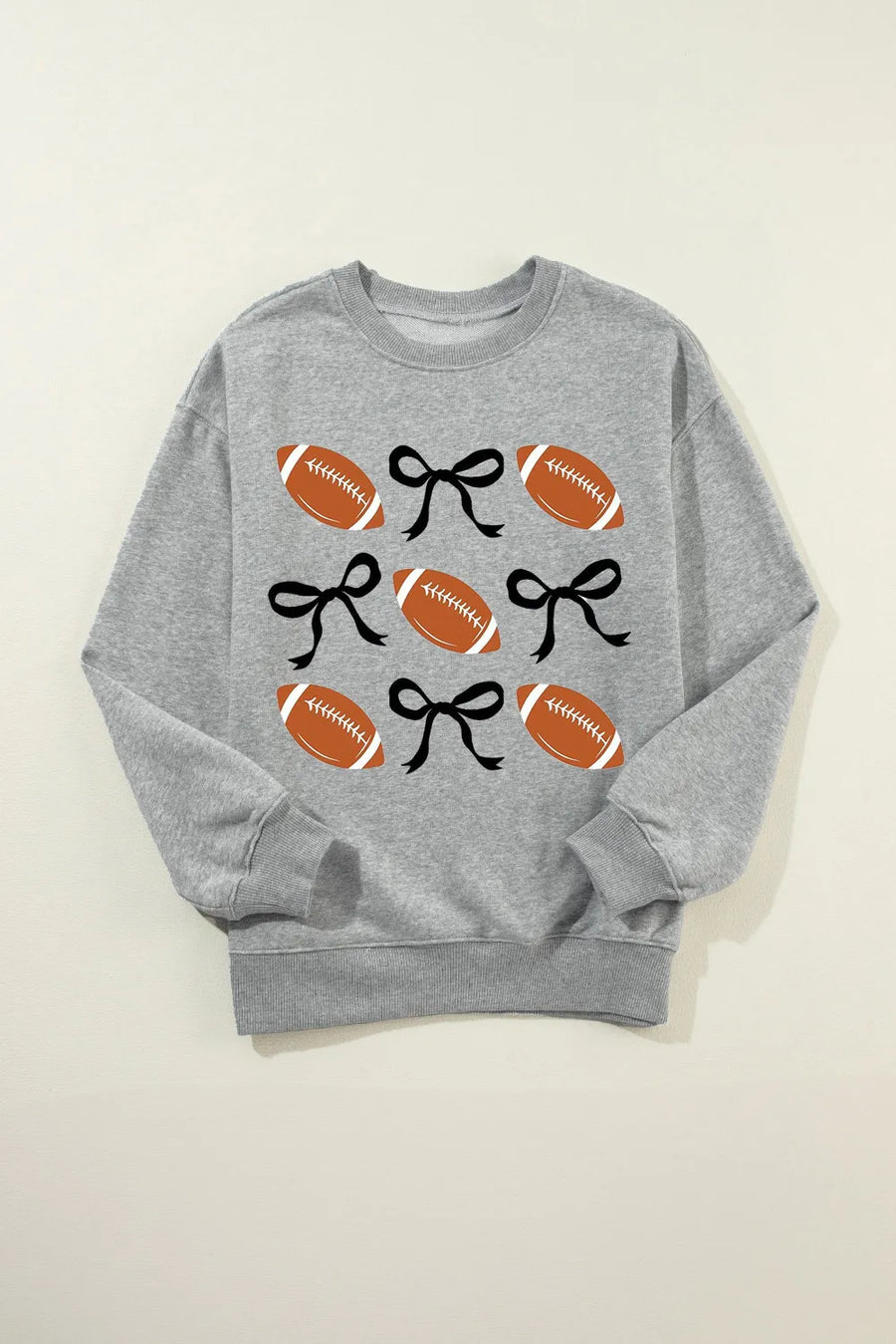 Gray sweatshirt with a grid pattern of footballs and black bows.