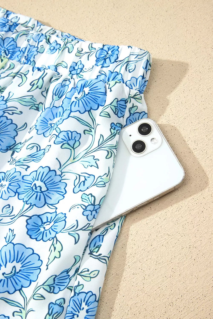 Floral print loungewear shorts with a white phone in the pocket.