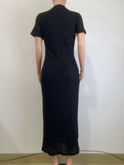 Black textured midi dress with short sleeves and a high neckline, featuring a subtle gold button detail.