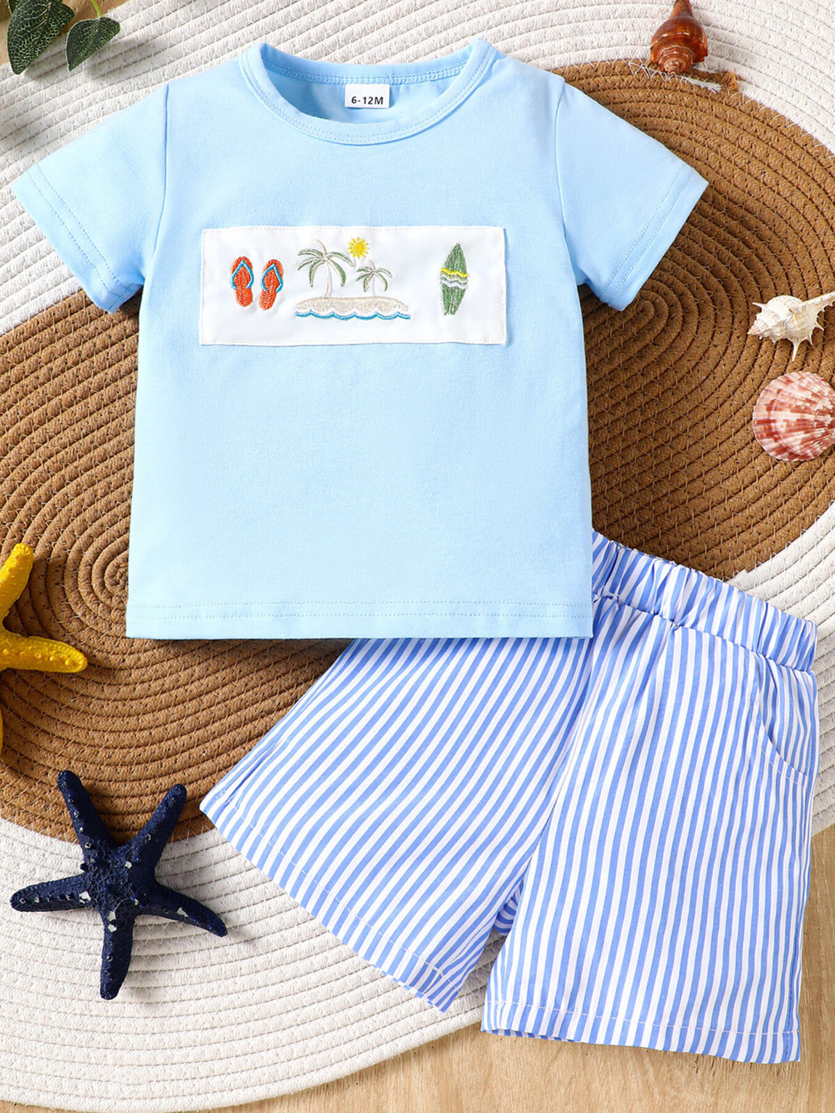 Baby blue cotton t-shirt with embroidered beach scene and blue striped shorts.