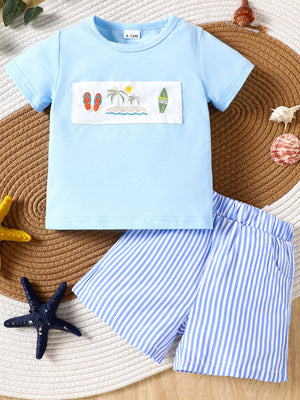 Baby blue cotton t-shirt with embroidered beach scene and blue striped shorts.