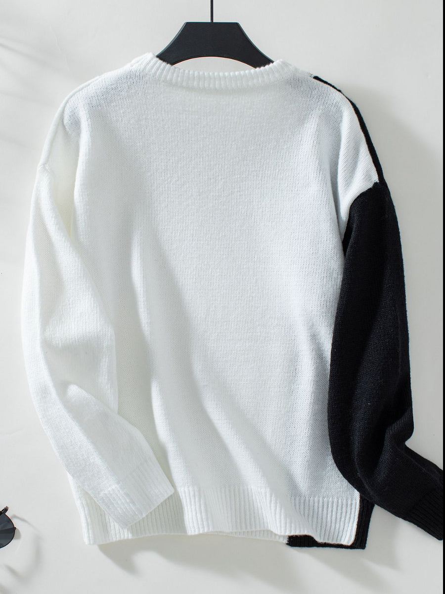 Colorblock knit sweater in white with black raglan sleeves and crewneck.