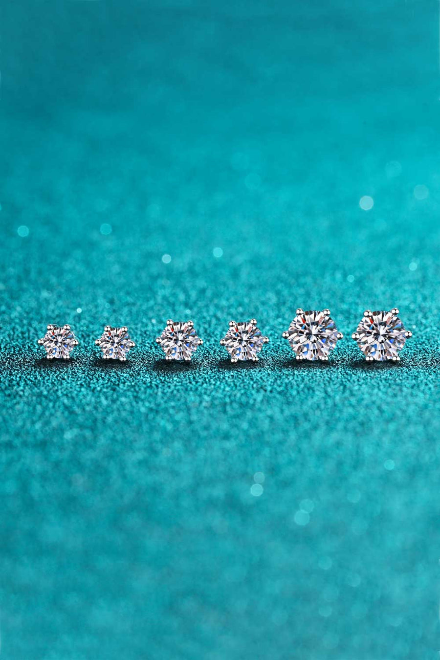 Six-prong moissanite stud earrings in silver, showing multiple sizes with brilliant cut stones.