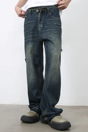 Baggy dark navy denim jeans with distressed knee slits and whiskering detail.