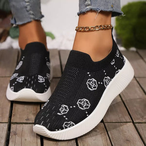 Black mesh slip-on sneakers with white pattern and white sole.