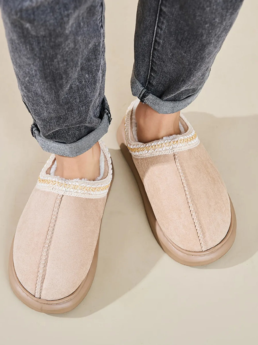 Tan shearling house slippers with embroidered trim and faux fur lining.