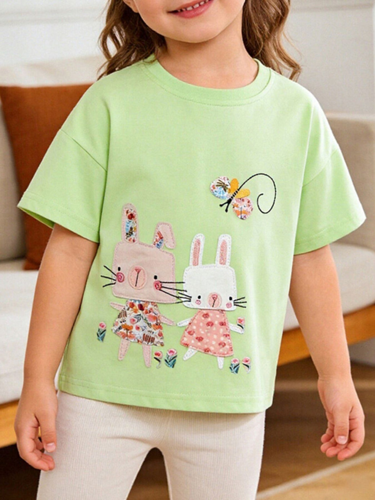 Light green short sleeve tee with appliqued bunnies and butterfly, floral dress detail.