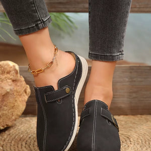 Black slip-on flats with buckle detail and contrast stitching.