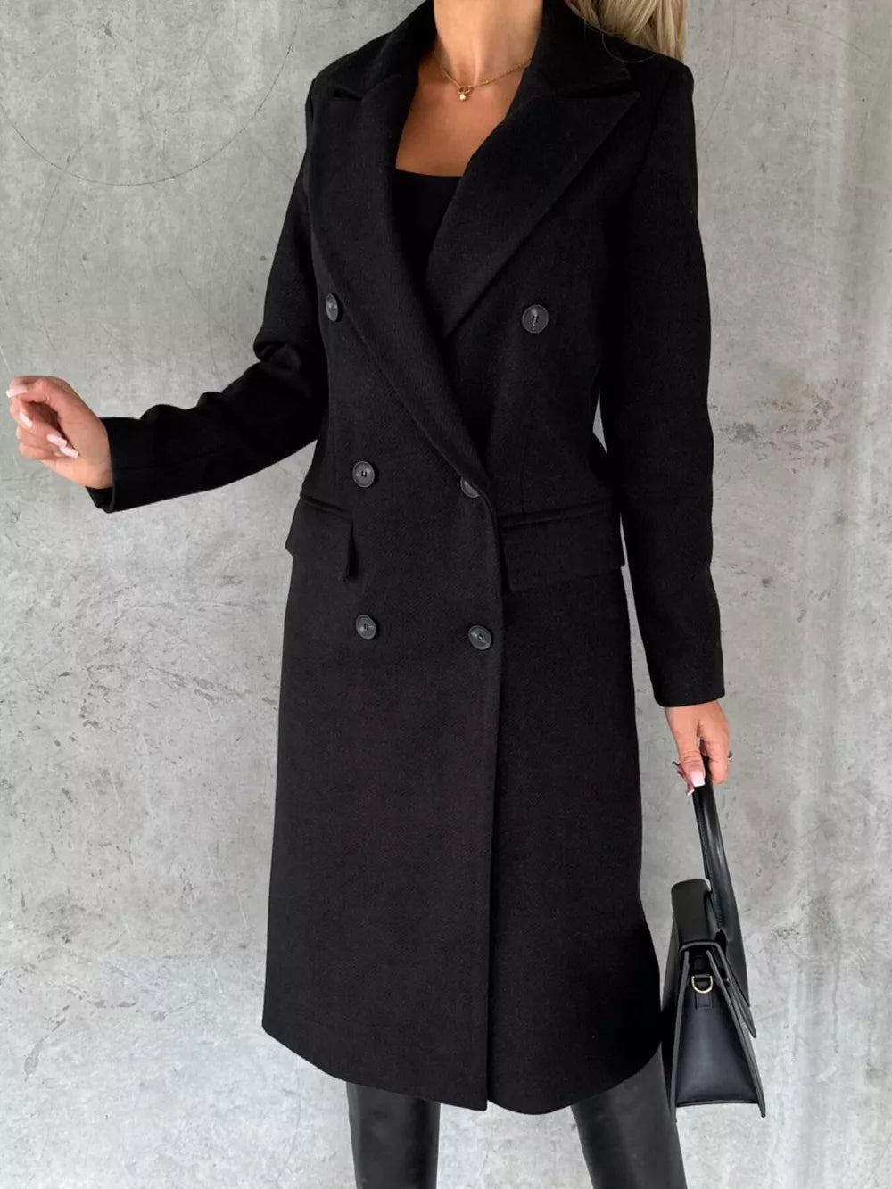 Black double-breasted longline trench coat with button details and notched lapels.