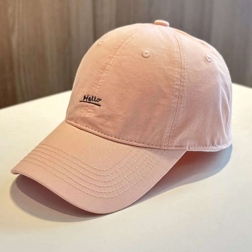 Pink baseball cap with embroidered "Hello" detail