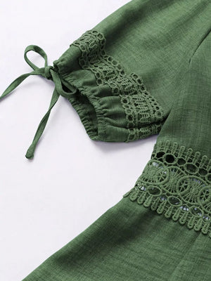 Green mini dress with lace trim on sleeves and hem, featuring tie details on sleeves.