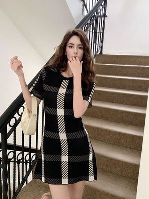 Black and white plaid mini dress with short sleeves and a crew neck, styled with a cream handbag.