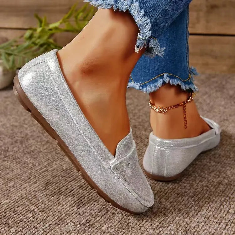 Silver metallic loafer flats with subtle stitching and a brown sole.