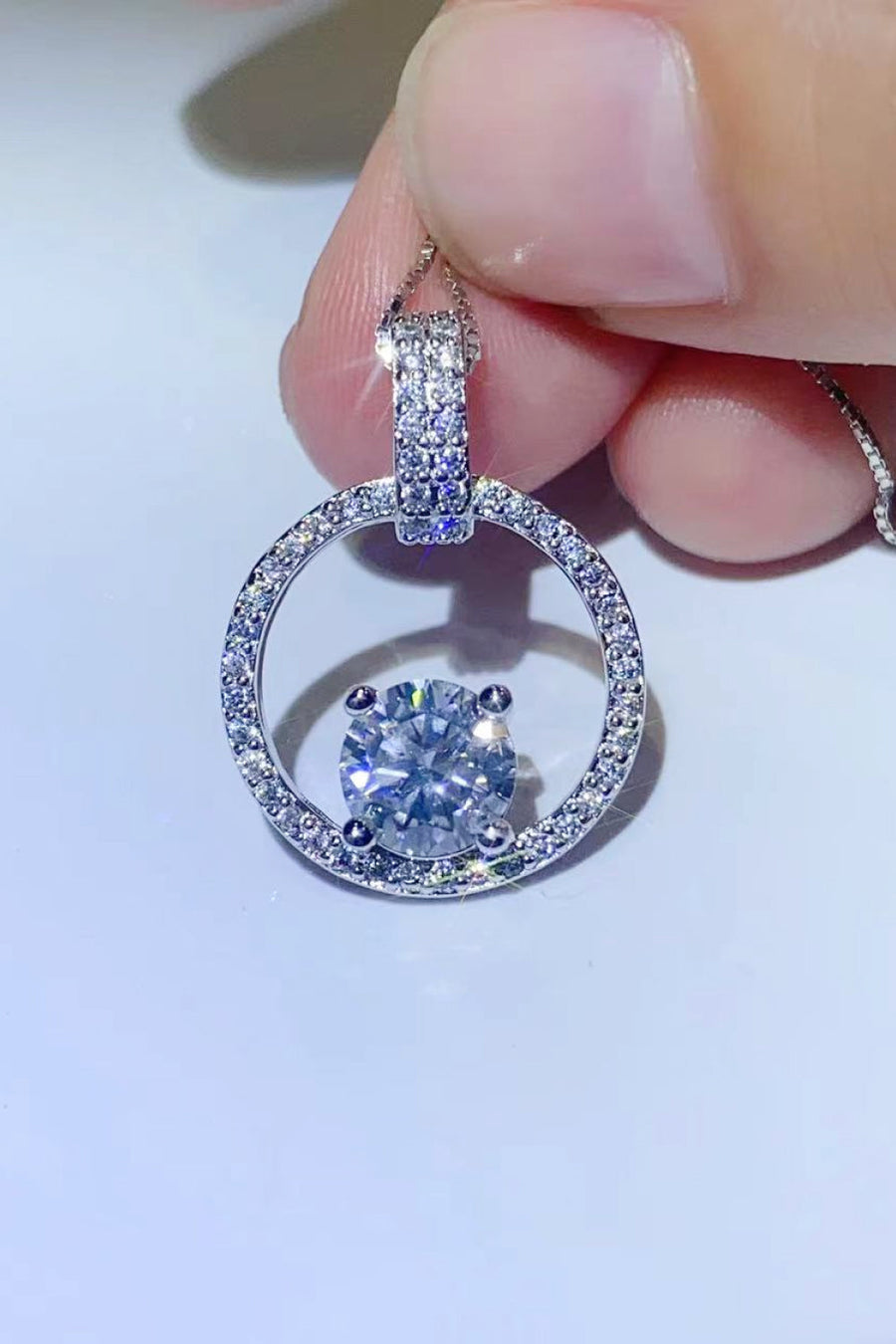 Silver halo moissanite circle pendant necklace with pave diamond bail and center stone.