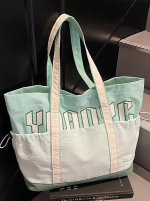 Green and white drawstring shoulder bag with bold lettering and front pockets