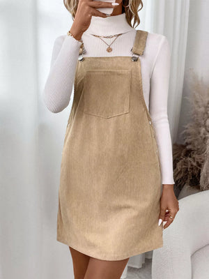 Tan corduroy overall dress with a bib pocket and adjustable straps.