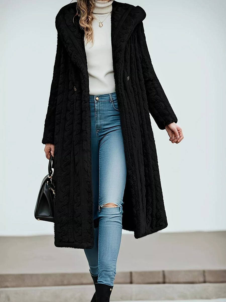 Black hooded longline button up outerwear with textured pattern, worn open over a cream turtleneck and ripped jeans.