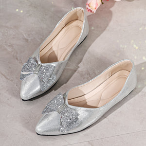 Silver pointed toe flats with glitter bows and rhinestone accents.