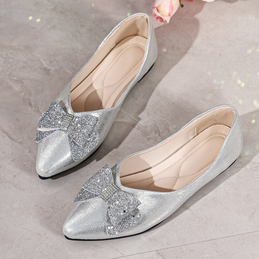 Silver pointed toe flats with glitter bows and rhinestone accents.