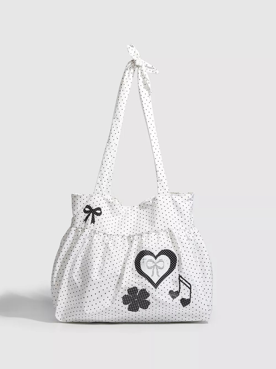 White polka dot canvas shoulder bag with heart, bow, clover, and music note appliqués.