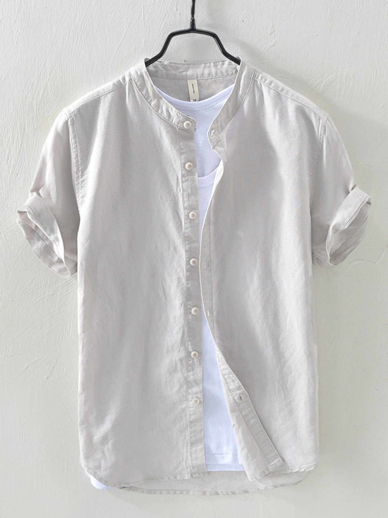Light gray linen short sleeve shirt with band collar and rolled cuffs, layered over a white t-shirt.
