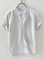 Light gray linen short sleeve shirt with band collar and rolled cuffs, layered over a white t-shirt.