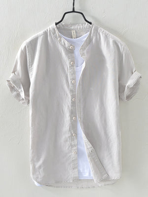 Light gray linen short sleeve shirt with band collar and rolled cuffs, layered over a white t-shirt.