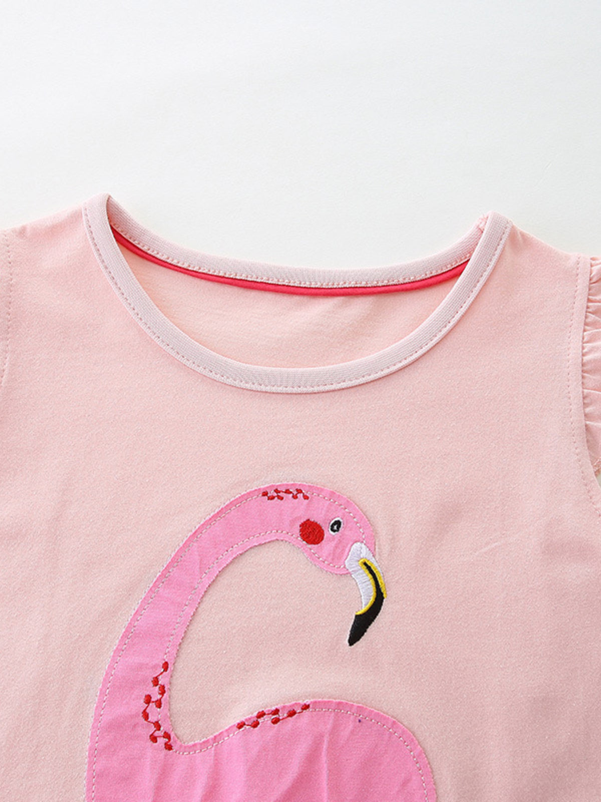 Pink cotton baby dress with flamingo appliqué and ruffled sleeves.