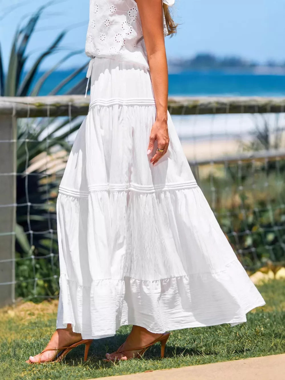 White tiered maxi skirt with delicate pleating and a flowing silhouette.