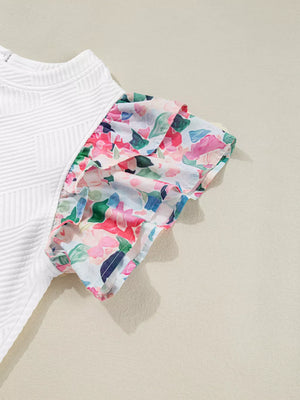 White geometric knit top with colorful floral ruffled sleeves.