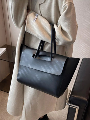Black PU leather tote shopper bag with a flap detail and cutout handle.