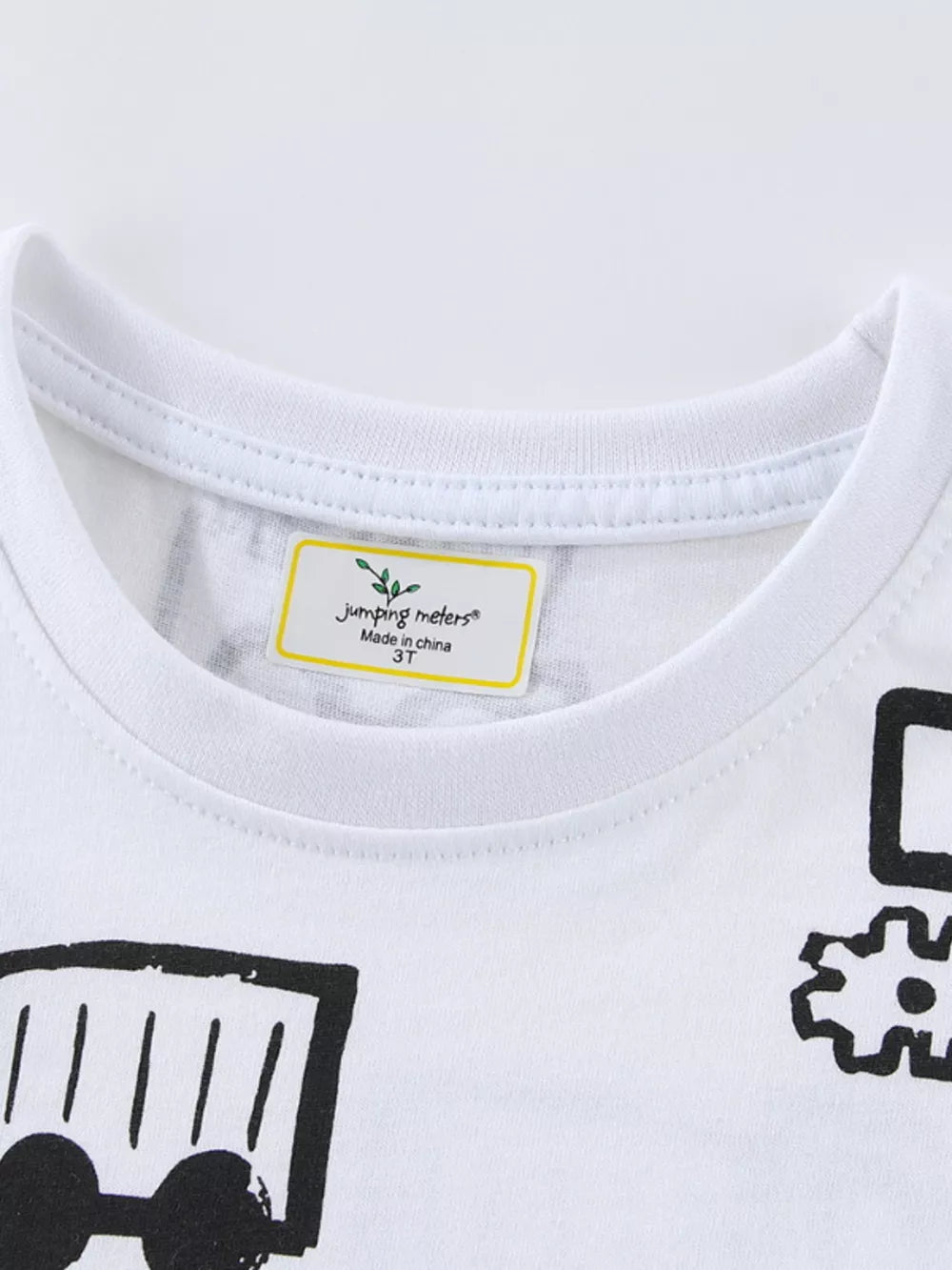 White cotton t-shirt with black construction vehicle graphic print and tag detail.
