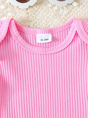 Pink ribbed cotton baby top with ruffle trim and daisy overalls detail