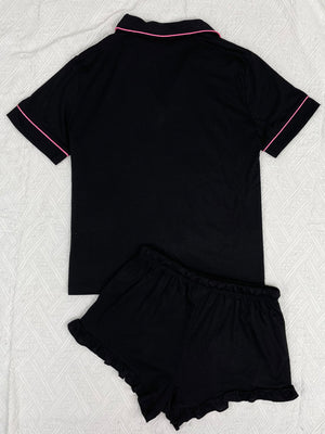Black pajama set with pink trim and ruffled shorts