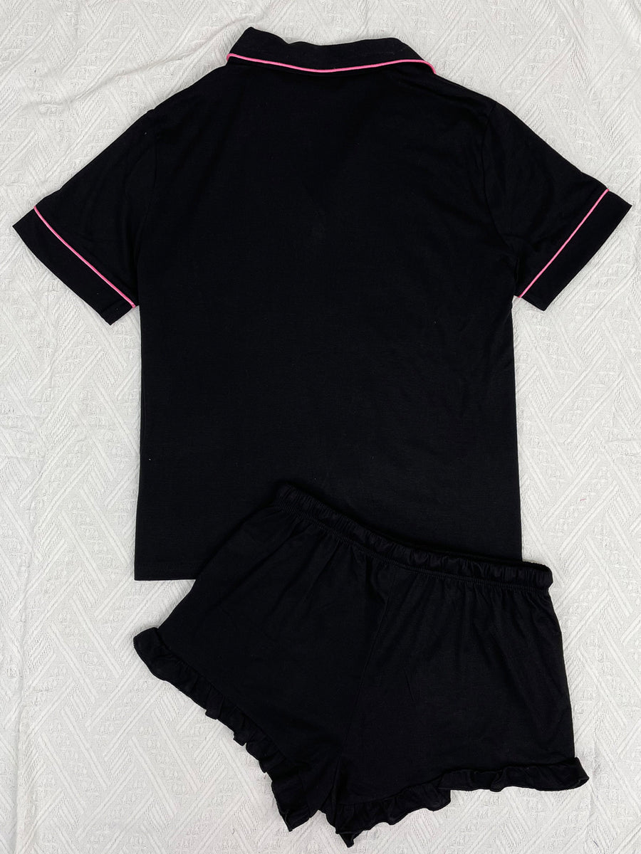 Black pajama set with pink trim and ruffled shorts