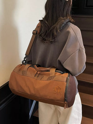 Brown Oxford cloth duffel bag with adjustable strap and carry handles, featuring a mesh side detail.