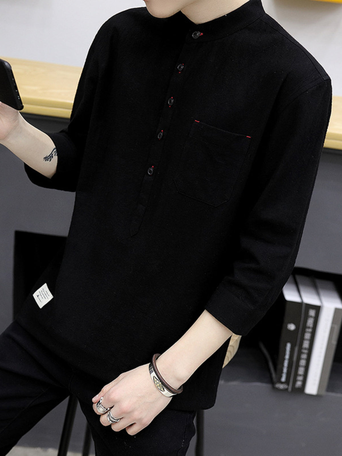 Black cotton shirt with mandarin collar, button detail, and chest pocket.
