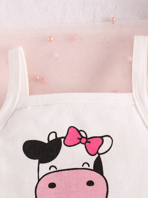 Baby cotton tank with cow print and pink bow detail, layered over sheer pink fabric with pearls.