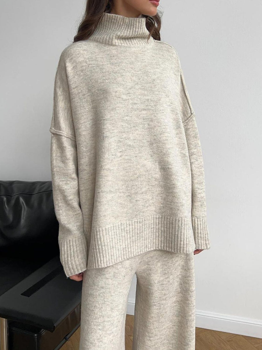 Oversized beige turtleneck lounge set with wide-leg pants and ribbed cuffs and hem.