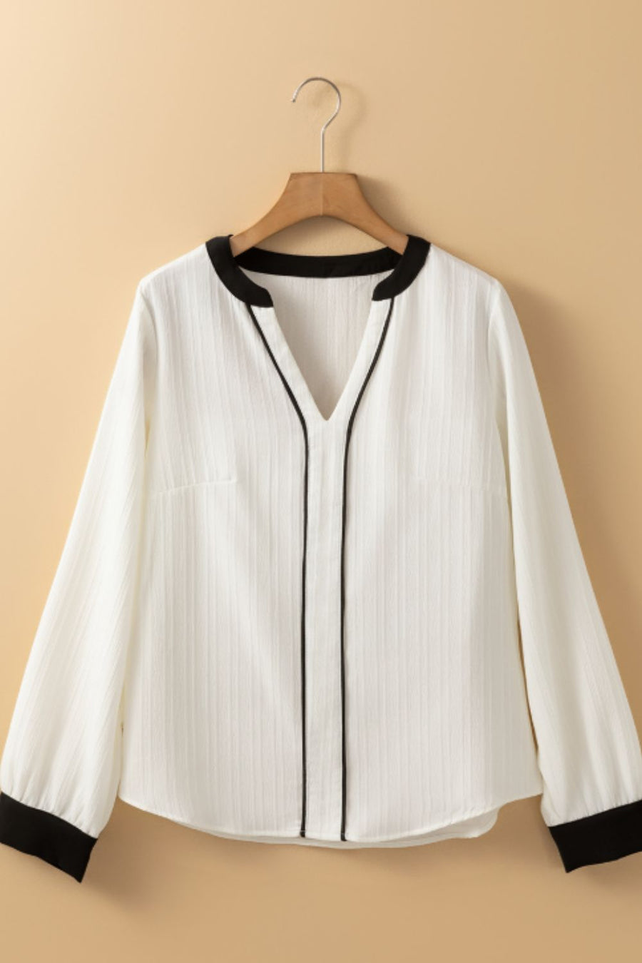 White textured V-neck blouse with black trim and cuffs.