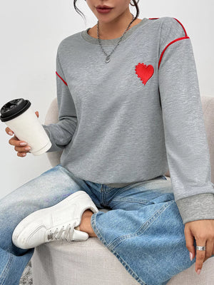 Gray sweatshirt with red heart embroidery and red trim detail on shoulders.