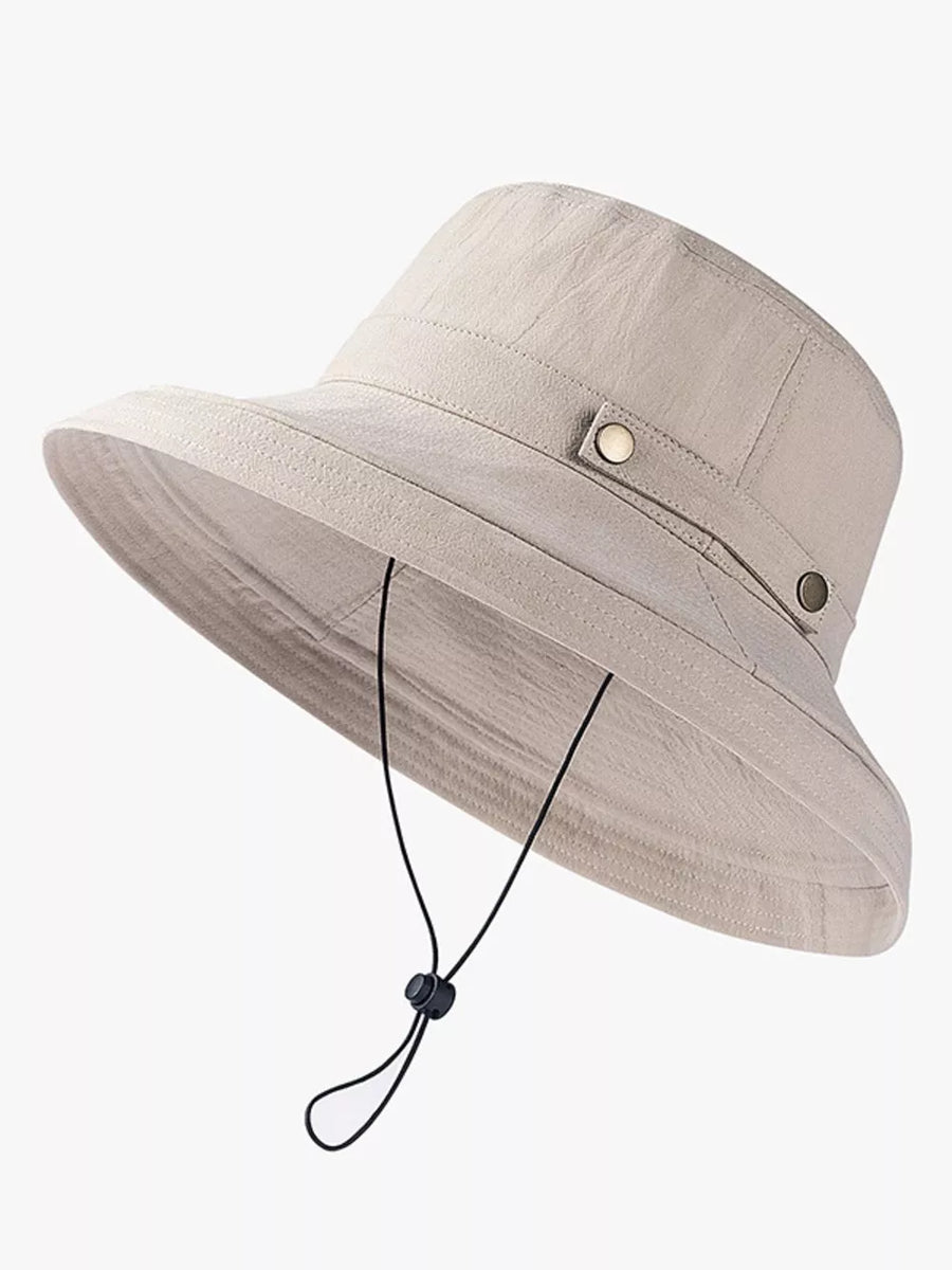 Khaki cotton bucket hat with wide brim, brass hardware, and chin strap.