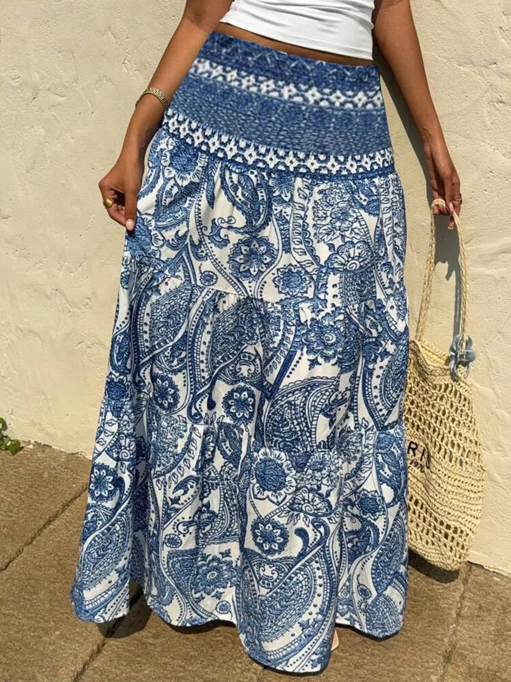 Maxi skirt with blue and white paisley print, smocked waistband, and tiered hem.