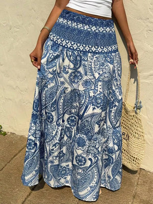 Maxi skirt with blue and white paisley print, smocked waistband, and tiered hem.