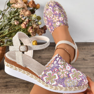 Floral espadrille wedge sandals with adjustable strap and round toe in purple.