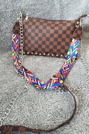 Brown checkered shoulder bag with studded trim and a colorful patterned strap.
