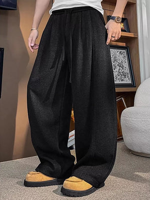 Black sweatpants with a loose fit and drawstring waist, styled casually.