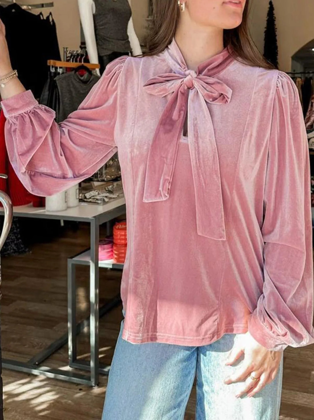 Chic velvet tie-neck blouse in dusty pink with puff sleeves and ruffled cuffs.